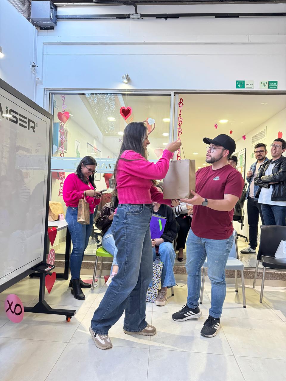 Entrega de un detalle entre compañeros durante Amor y Amistad